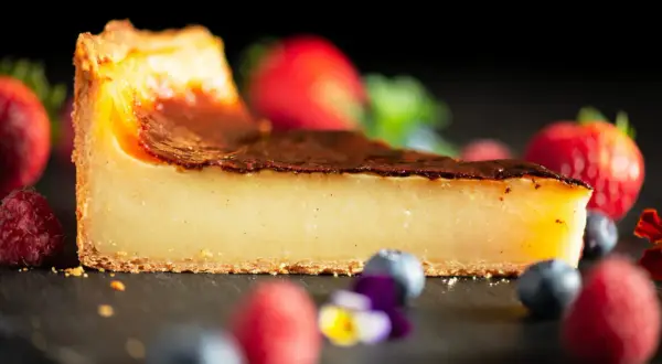 Tranche de flan pâtissier onctueux, avec une croûte dorée et des fruits rouges frais. Un délice pour les yeux et les papilles.