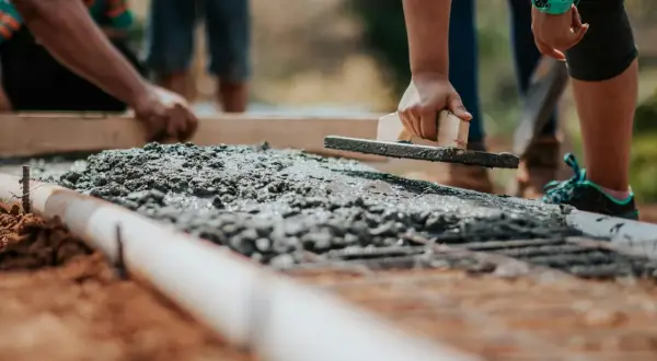 Pracownicy wyrównują świeży beton kielnią. Zastanawiasz się, ile kosztuje metr sześcienny betonu?