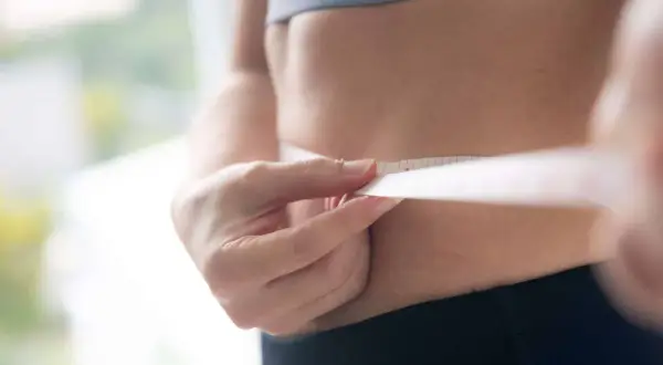Misura della vita con metro, per capire quante calorie bisogna bruciare al giorno per raggiungere i propri obiettivi di benessere.