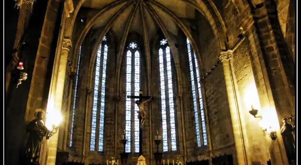 Interior de la iglesia San Francisco de Viveiro, con un crucifijo imponente y vitrales góticos.