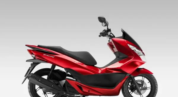 Czerwony skuter Honda PCX 125 na białym tle, widok z boku.