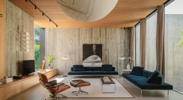 Interni in stile brutalist con pareti in cemento grezzo, soffitto in legno e mobili moderni.