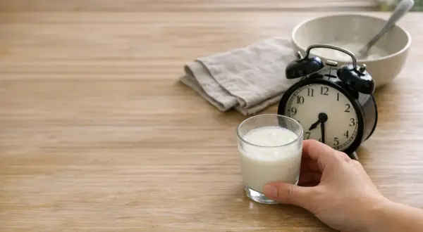 Un bicchiere di kefir pronto per essere gustato. L'orologio indica che è ora di bere kefir la sera.
