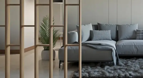 Ein modernes Wohnzimmer mit einer stilvollen Trennwand, die man auch selber bauen könnte. Ein bequemes Sofa und eine Pflanze schaffen Gemütlichkeit.
