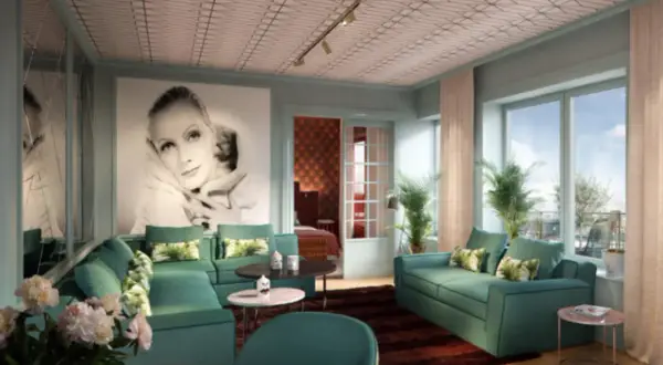 Ett lyxigt vardagsrum i art deco-stil med en stor bild av Greta Garbo, smaragdgröna soffor och ett mönstrat tak. En elegant inredning som andas **art deco Stockholm**.