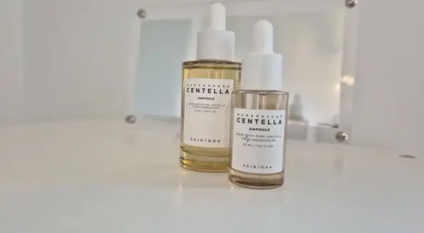 Dwie buteleczki z pipetką zawierające **centella ampoule** od SKIN1004, jedna większa, druga mniejsza, stoją na białej powierzchni.