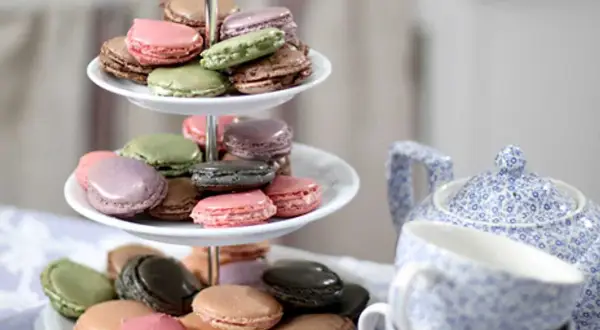 Färgglada macarons på ett tårtfat, redo att avnjutas. Ett perfekt macarons recept för fika.