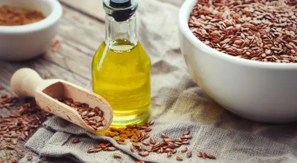 Olio di lino per pavimenti in graniglia, con semi sparsi e una ciotola piena.