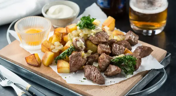 Biff Rydberg-inspirerad rätt med tärnad biff, stekt potatis, lök och en skål med sås. Ett perfekt biff rydberg recept för en härlig middag.