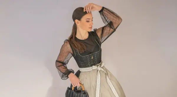 Frau im modernen mini dirndl extra kurz mit transparentem Oberteil und auffälliger Schürze.
