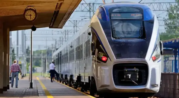 Pociąg Intercity na peronie. Zastanawiasz się, czy można jechać wcześniejszym pociągiem Intercity? Zegar na stacji pokazuje czas.