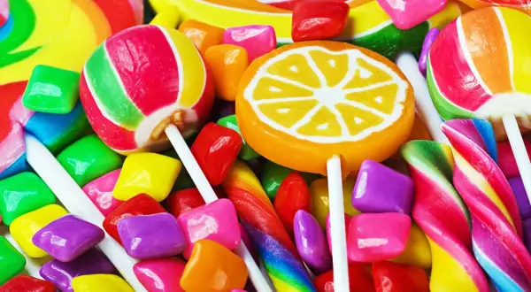 Un surtido vibrante de dulces, incluyendo piruletas, caramelos de goma y bastones de caramelo, que evocan la alegría de los dulces en inglés.