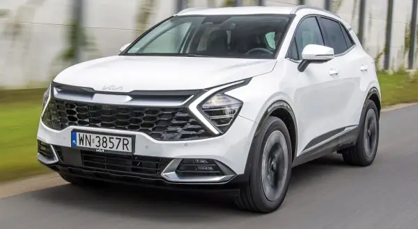 Biała Kia Sportage 1.6 benzyna w ruchu, z widocznym grillem i reflektorami.