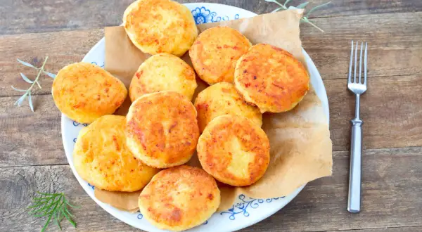 Talerz pełen złotych, puszystych arepas, ułożonych na brązowym papierze. Obok widelec i gałązki ziół.
