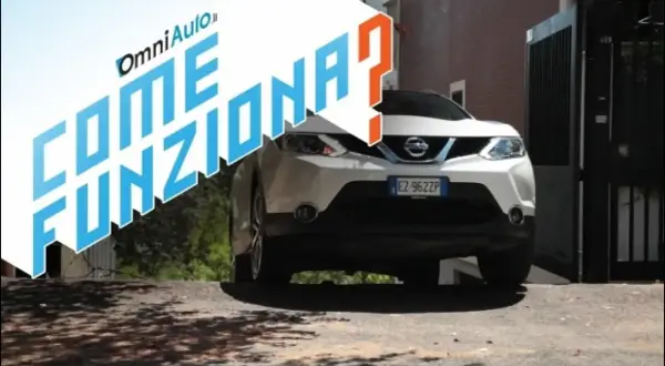 Nissan bianco su strada in salita, con testo "Come funziona?". Spiegazione del sistema hill holder.