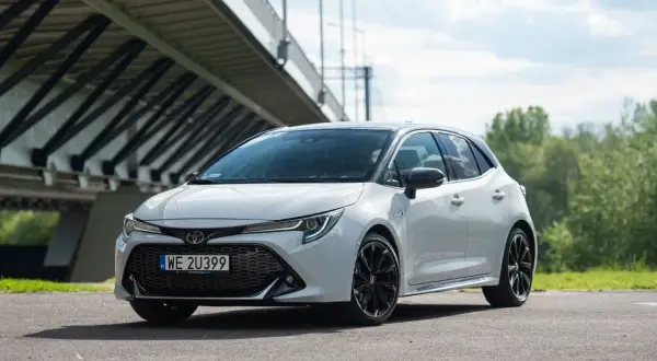 Biała Toyota Corolla GR Sport z czarnymi felgami stoi pod mostem.