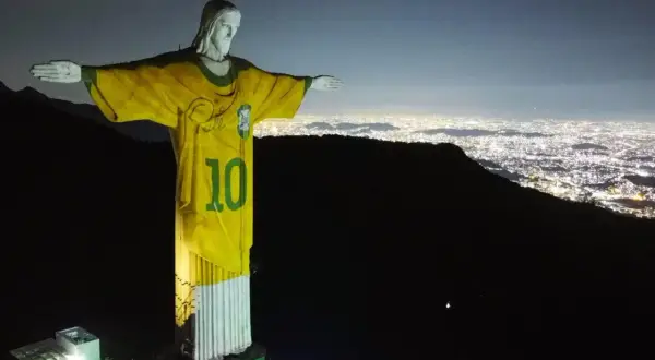 Jezus w Rio w koszulce z numerem 10, symbolizujący brazylijską dumę narodową, góruje nad nocnym miastem.