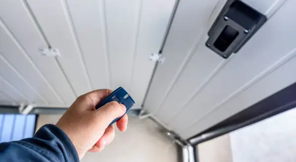 Main tenant utilise une télécommande pour motoriser une porte de garage.