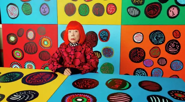 Yayoi Kusama w otoczeniu swoich kolorowych dzieł, pełnych kropek i wirów.