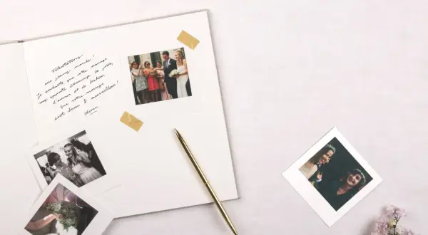 Vœux de mariage manuscrits sur un album, avec des photos instantanées de la cérémonie et du couple. Un stylo doré repose à côté.
