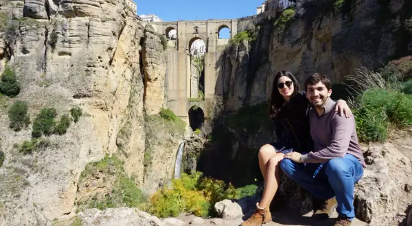 Pareja sonriente posa ante el Puente Nuevo de Ronda, una maravilla para visitar en Ronda en 1 día.