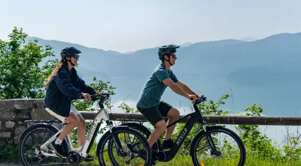 Zwei Personen genießen e bike touren mit Blick auf einen See und Berge.