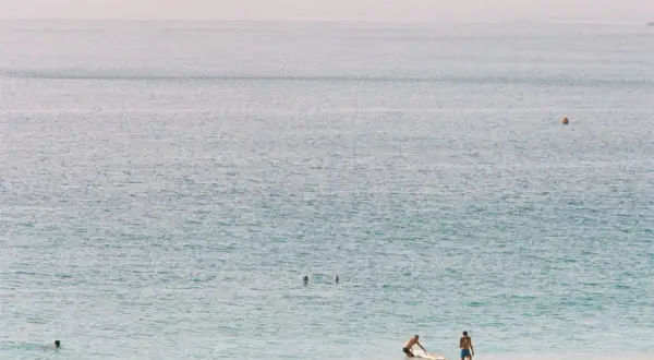 Ludzie odpoczywają na plaży, w tle widać ocean i wyspy. Zastanawiasz się, ile trwa lot na Wyspy Zielonego Przylądka?