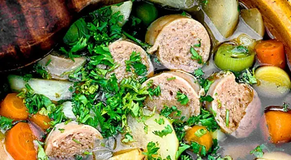 En närbild på en mustig korvgryta med potatis, morötter och purjolök, toppad med färsk persilja. Ett perfekt korvgryta recept för kalla dagar.
