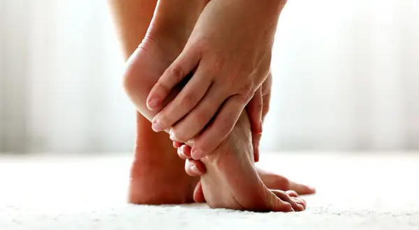 Mani che massaggiano un piede, alleviando il dolore al piede sopra.