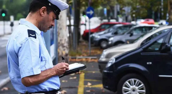 Agente di polizia scrive una multa. Cosa succede se non pago una multa? Potrebbe comportare sanzioni aggiuntive e problemi legali.