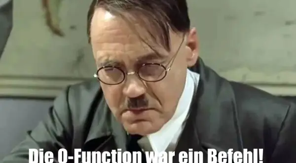 Adolf Hitler, mit Brille und Schnurrbart, blickt nach unten. Der Text "Die Q-Function war ein Befehl!" könnte ihn "triggered" haben.