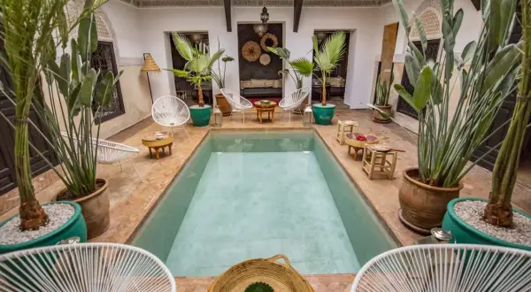 Ein Riad in Marokko: Ein Innenhof mit Pool, Pflanzen und Sitzgelegenheiten, typisch für marokkanische Architektur.