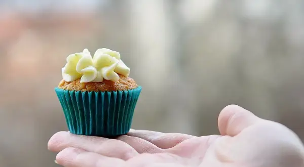 En hand håller en vackert dekorerad muffin, redo att baka muffins.