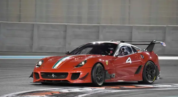 Czerwony Ferrari FXX K z numerem 4 na torze wyścigowym, gotowy do pokonania kolejnego zakrętu.