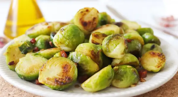 Plato de coles de Bruselas al horno, doradas y tiernas, con trocitos de bacon crujiente. Un manjar irresistible.