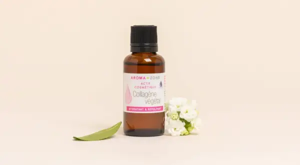 Flacon de collagène végétal Aroma-Zone, aux bienfaits hydratants et repulpants, entouré de fleurs blanches et d'une feuille verte.