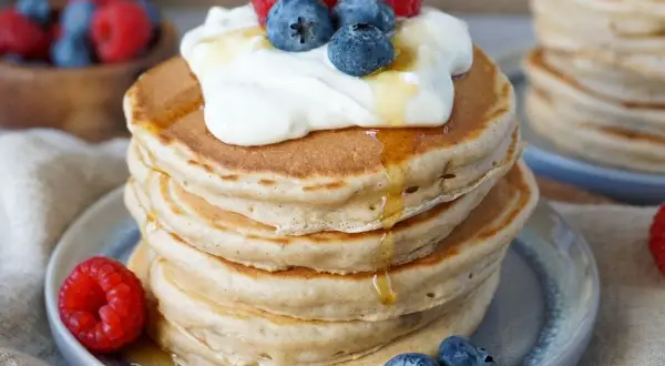 Fluffige Bananenpfannkuchen mit Sahne, Beeren und Honig. Ein köstlicher Frühstückstraum!