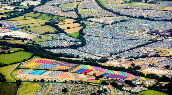 Aerial view of a vibrant Glastonbury map, showcasing a sprawling landscape of colorful tents and parked cars, a testament to the festival's immense scale.