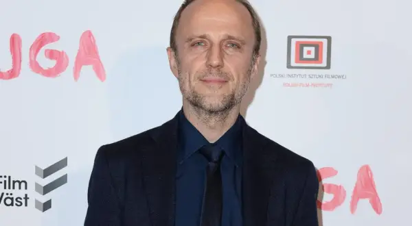 Łukasz Simlat, znany z wielu polskich filmów, na tle napisu "JUGA" i logo Polskiego Instytutu Sztuki Filmowej.