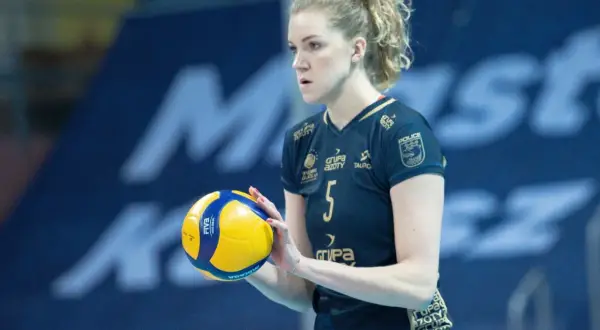 Agnieszka Korneluk, siatkarka z numerem 5, trzyma piłkę. Jej mąż pewnie kibicuje jej z trybun.