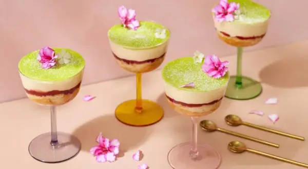 Fyra vackra prinsesstårtor i glas, dekorerade med blommor och strösocker. Perfekt för en festlig fika.