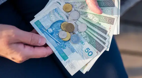 Dłonie trzymają polskie banknoty i monety. Ile razy można dać darowiznę dziecku? Zależy od kwoty i potrzeb.