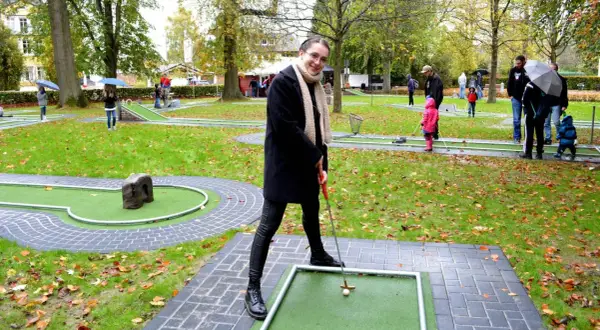 Frau spielt Minigolf in Hennef, im Hintergrund spielen weitere Personen.