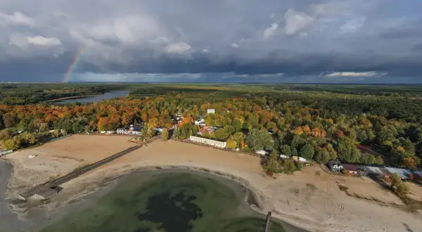 Jesioro Niedzięgiel jesienią, z tęczą na niebie i piaszczystą plażą.