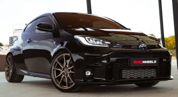 Czarny Toyota Yaris Sport z brązowymi felgami, gotowy do dynamicznej jazdy.