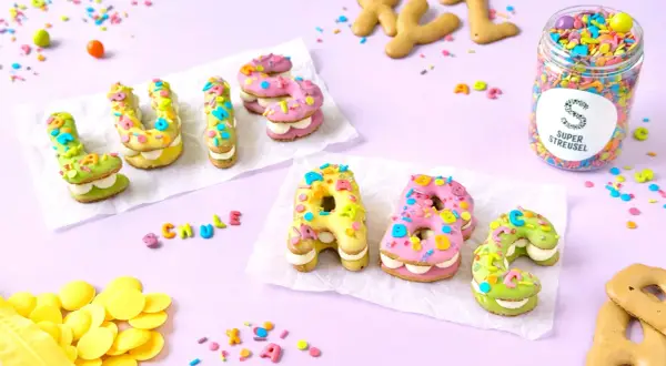 Bunte Buchstabenkekse, inspiriert von einem russisch brot rezept, mit Zuckerguss und Streuseln verziert.