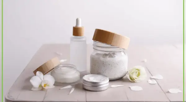 Naturalne kosmetyki z ethylhexyl stearate: kremy, serum i peeling w słoiczkach z bambusowymi nakrętkami, ozdobione kwiatami.