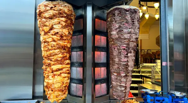 Dwa pionowe rożny z mięsem do kebaba, jeden z kurczaka, drugi wołowy. Zastanawiasz się, ile kcal ma mały kebab?