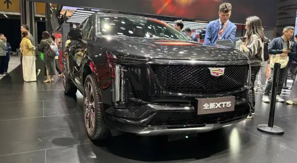 Elegancki, czarny Cadillac XT5 na wystawie. Ludzie oglądają nowy model, który przyciąga uwagę swoim designem.