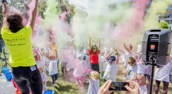 Kolorowy festiwal proszków w Kołobrzegu! Dzieci w białych koszulkach rzucają kolorowymi proszkami, tworząc radosną atmosferę. To świetne kołobrzeg atrakcje dla dzieci.